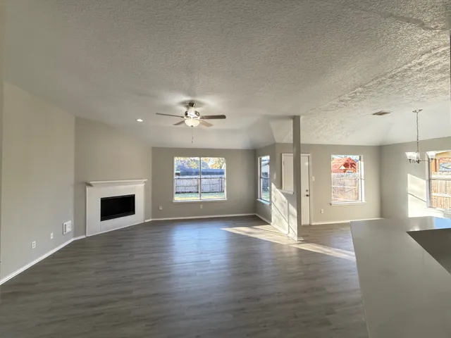 an empty room with windows fireplace and fans