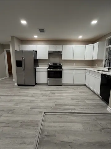 a large kitchen with stainless steel appliances granite countertop a stove and a refrigerator