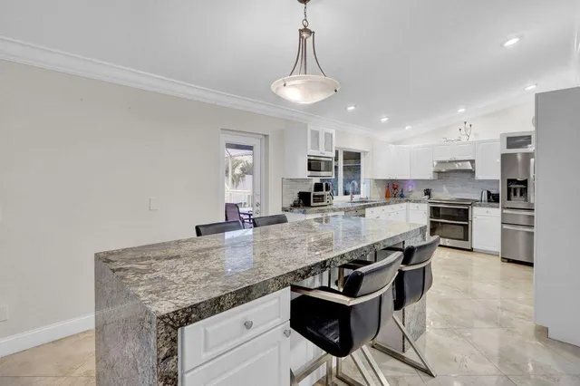 a large kitchen with granite countertop lots of counter top space and stainless steel appliances