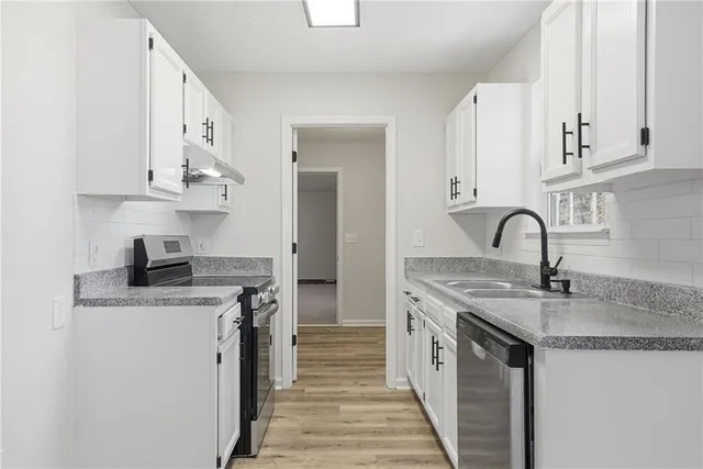 a kitchen with stainless steel appliances granite countertop a sink stove and cabinets