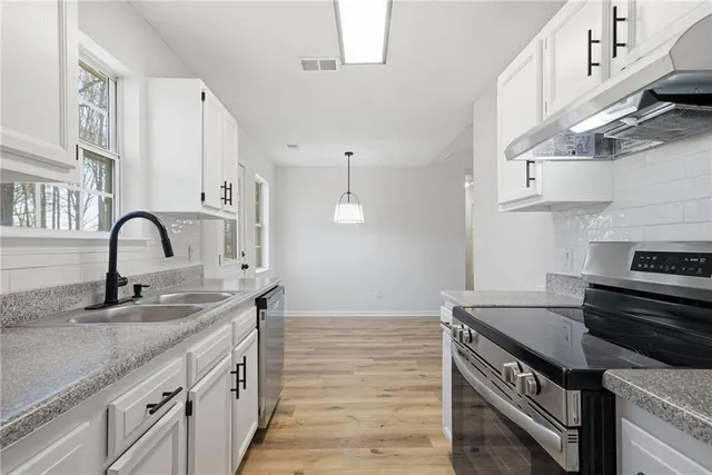 a kitchen with granite countertop a stove a sink and a refrigerator