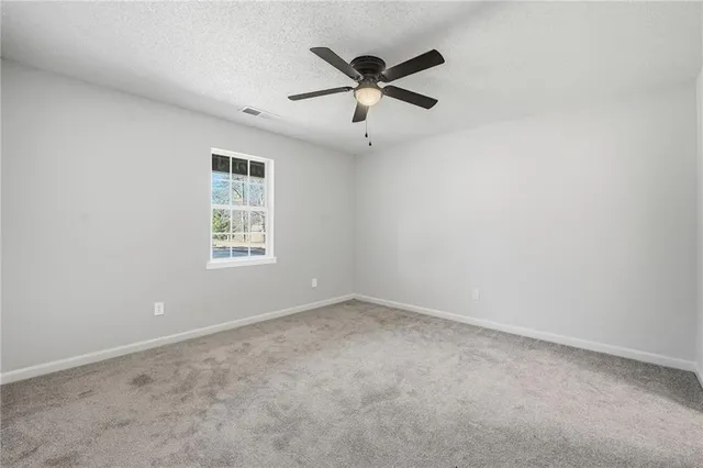 an empty room with a window and a fan
