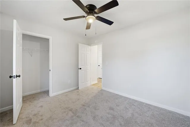 an empty room with a ceiling fan and carpet