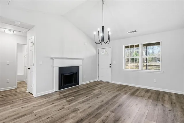 a view of empty room with wooden floor fireplace and window