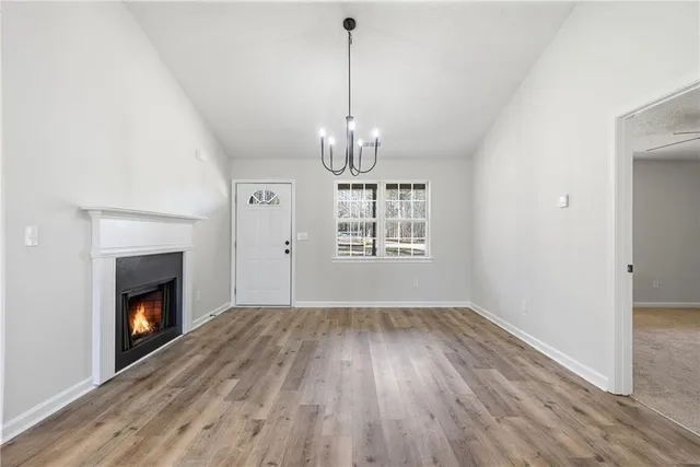 a view of empty room with wooden floor fireplace and a window