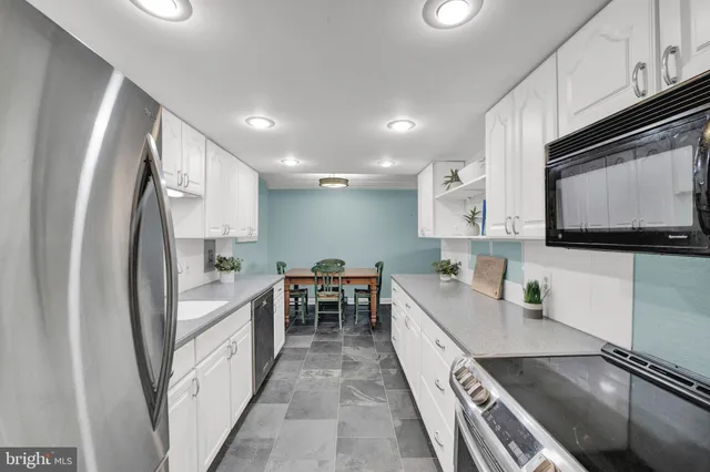 a kitchen with white cabinets and sink