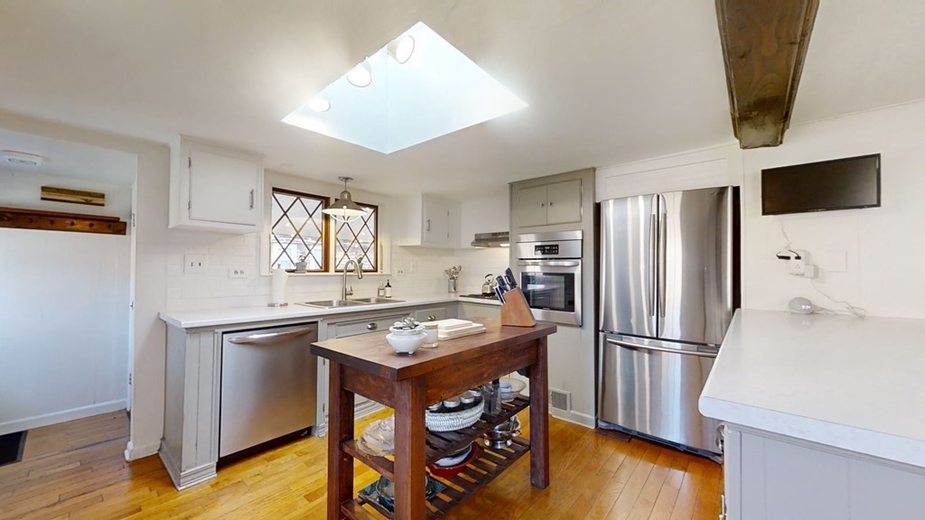 5 Pleasant Street Amesbury, MA 01913 - Photo 19 of 36 a kitchen with stainless steel appliances granite countertop a refrigerator a stove a sink dishwasher and white countertops with wooden floor