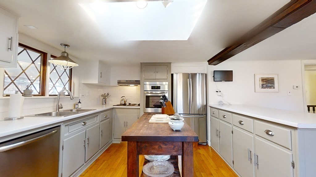 5 Pleasant Street Amesbury, MA 01913 - Photo 20 of 36 a kitchen with white cabinets a sink dishwasher and a stove with wooden floor