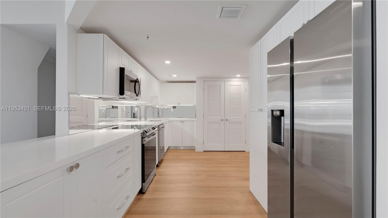 555 Northeast 34th Street, Unit 705 Miami, FL 33137 - Photo 2 of 28 a kitchen with white cabinets and stainless steel appliances