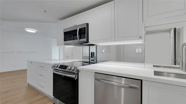 a kitchen with stainless steel appliances white cabinets and a sink