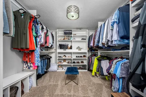 a view of walk in closet with clothes and shoes