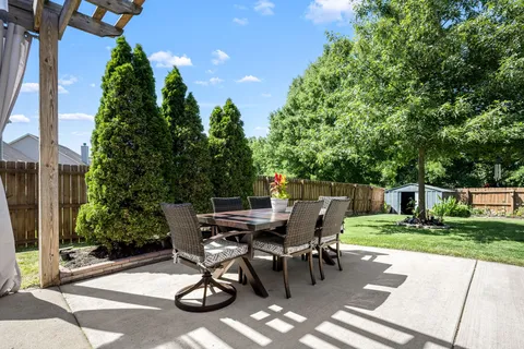 a view of a patio with table and chairs potted plants and floor to ceiling window