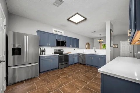 a kitchen with stainless steel appliances a sink a stove a refrigerator cabinets and a counter top space