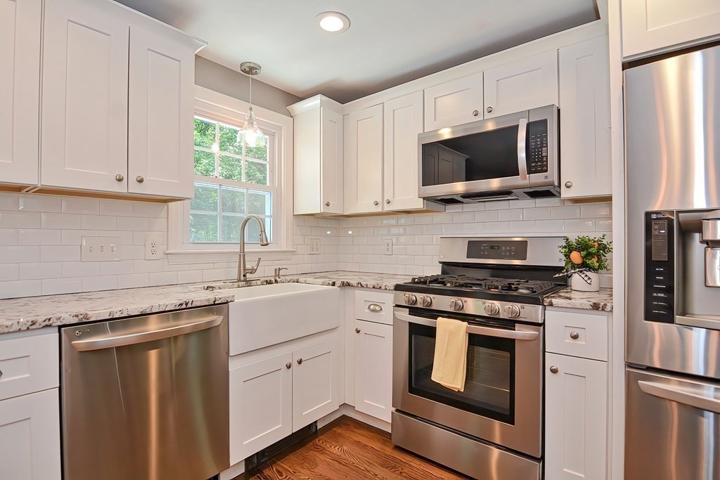 2 Labo Lane Bedford, MA 01730 - Photo 4 of 40 a kitchen with stainless steel appliances granite countertop white cabinets a sink a stove a microwave and wooden floors