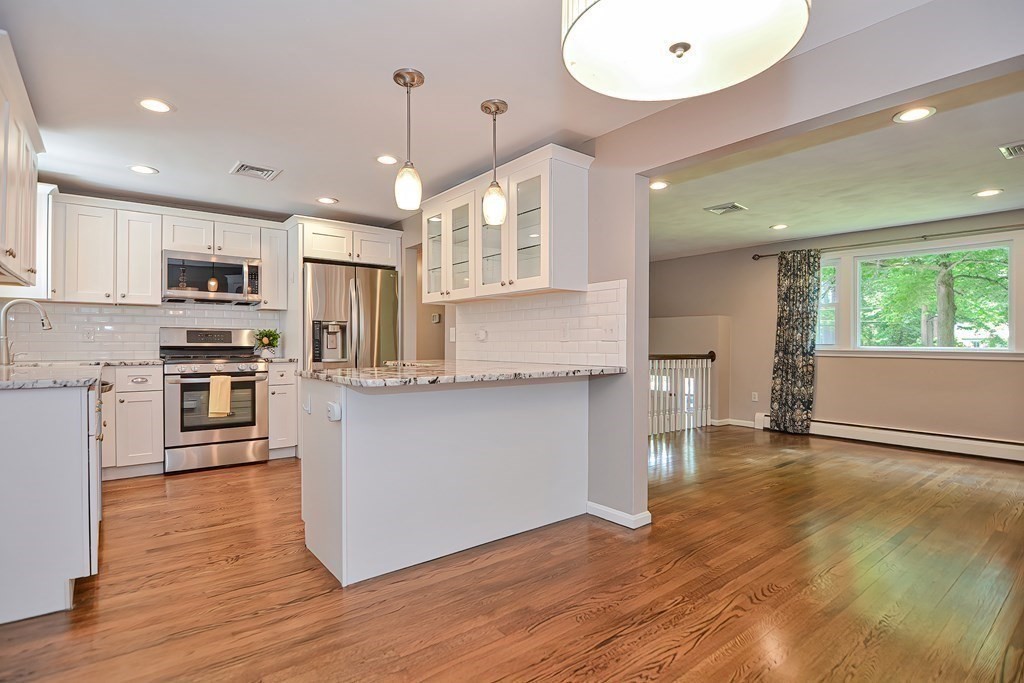 2 Labo Lane Bedford, MA 01730 - Photo 8 of 40 a kitchen with kitchen island granite countertop wooden floors and wide window
