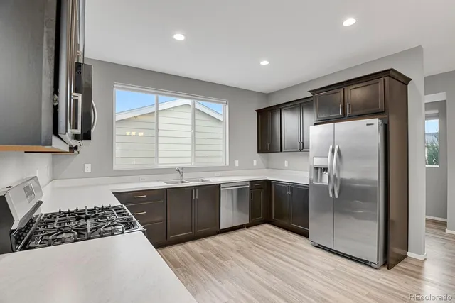 a kitchen with stainless steel appliances granite countertop a refrigerator a sink dishwasher a stove with wooden cabinets and floor