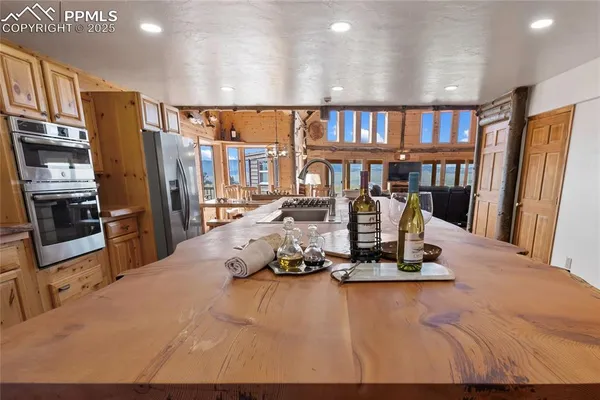 a kitchen with stainless steel appliances granite countertop a stove top oven a sink a dining table and chairs