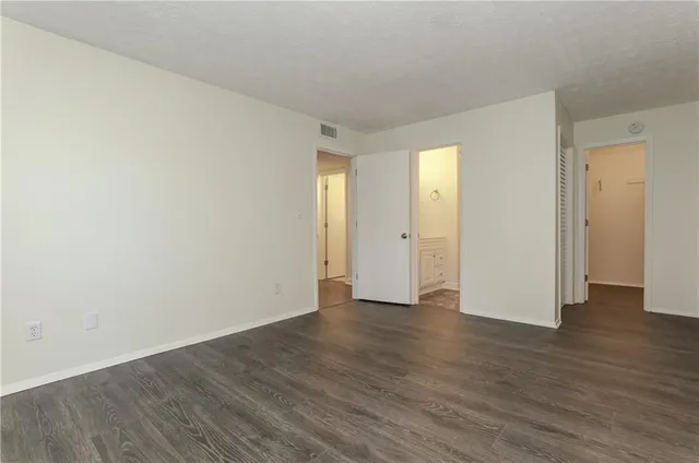a view of an empty room with wooden floor and closet