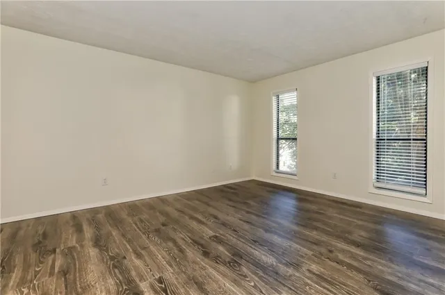a view of an empty room with wooden floor and window