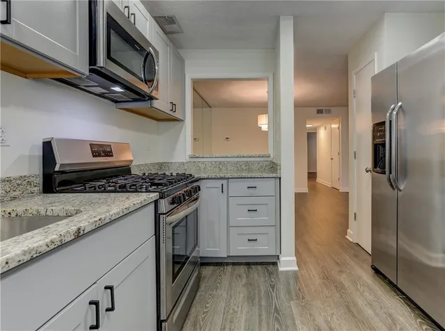 a kitchen with stainless steel appliances granite countertop a stove a sink and a refrigerator