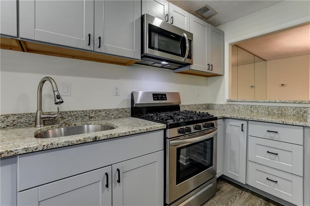 308 Wynnes Ridge Circle Southeast Marietta, GA 30067 - Photo 4 of 17 a kitchen with granite countertop white cabinets stainless steel appliances and a sink