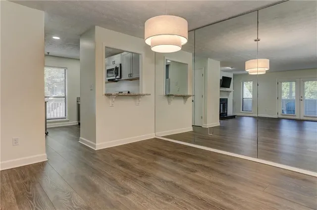 an empty room with wooden floor and a kitchen
