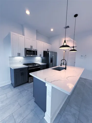 a kitchen with kitchen island a sink a stove a refrigerator and a kitchen island