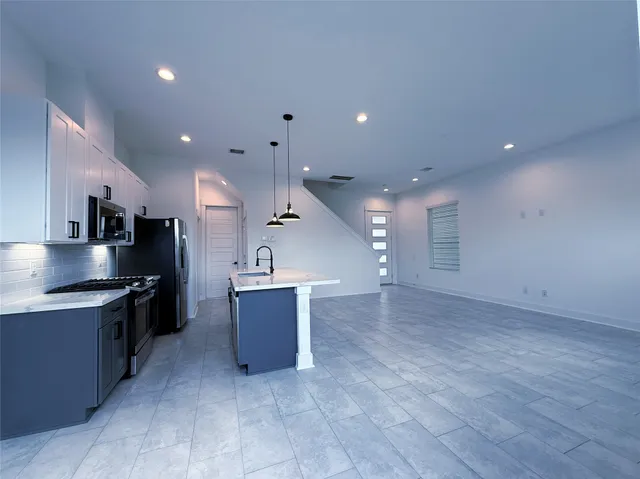 a large kitchen with stainless steel appliances a large counter top and a stove