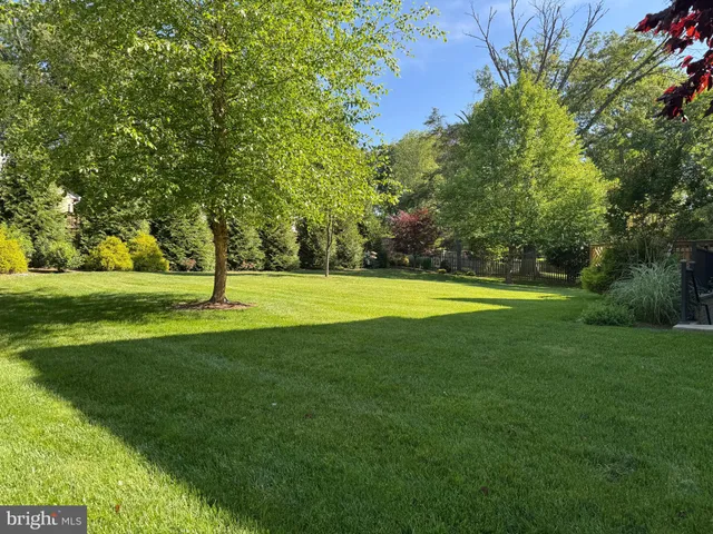 a view of an empty room with wooden floor fire place and a window