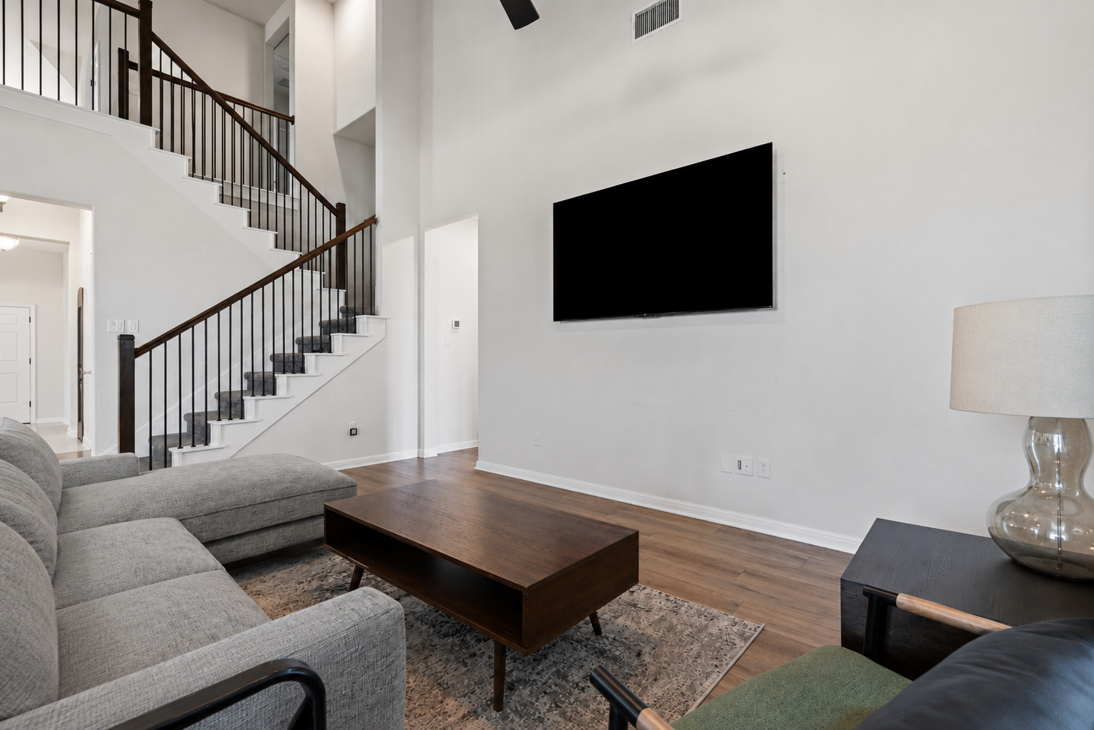 100 Panico Road Hutto, TX 78634 - Photo 10 of 28 A grand staircase with elegant railings ascends, complementing the lofty ceilings and rich wood flooring.