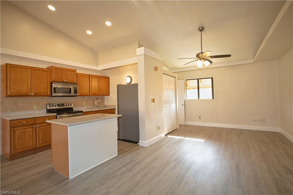 a kitchen with stainless steel appliances granite countertop a refrigerator a stove oven a sink dishwasher and white cabinets with wooden floor