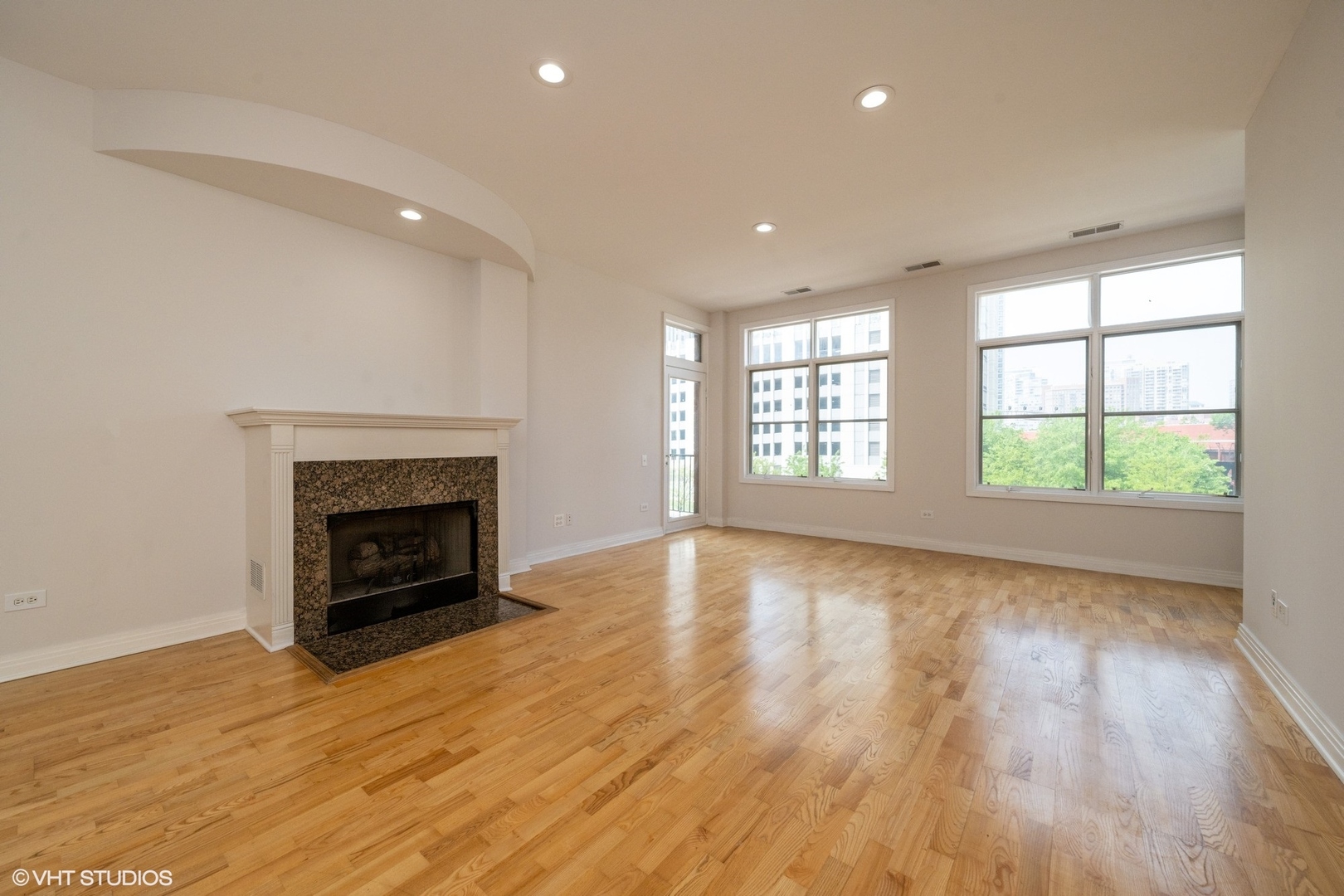 330 North Clinton Street, Unit 303 Chicago, IL 60661 - Photo 4 of 14 an empty room with wooden floor fireplace and windows