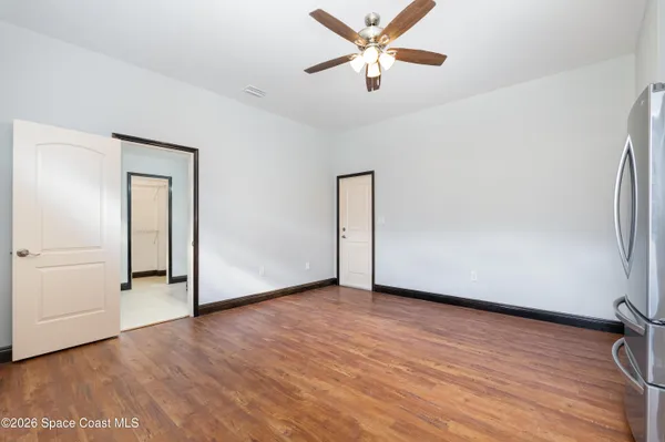 an empty room with wooden floor chandelier fan and windows