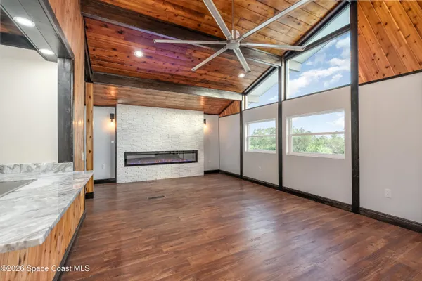 a view of an empty room with wooden floor and door