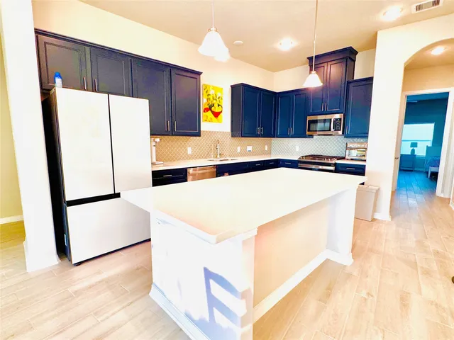 a large white kitchen with a large window and chandelier
