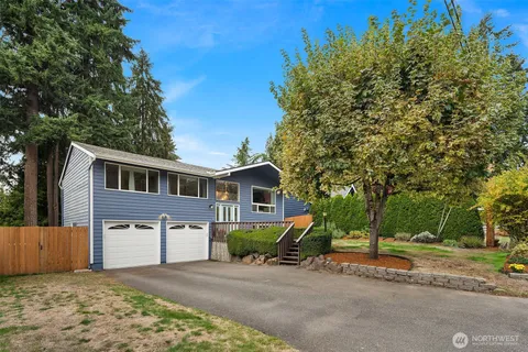 a front view of a house with a garden and trees