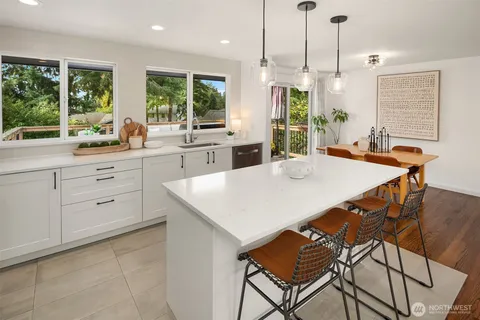 a kitchen with stainless steel appliances kitchen island granite countertop a stove a refrigerator a sink a dining table and chairs with wooden floor