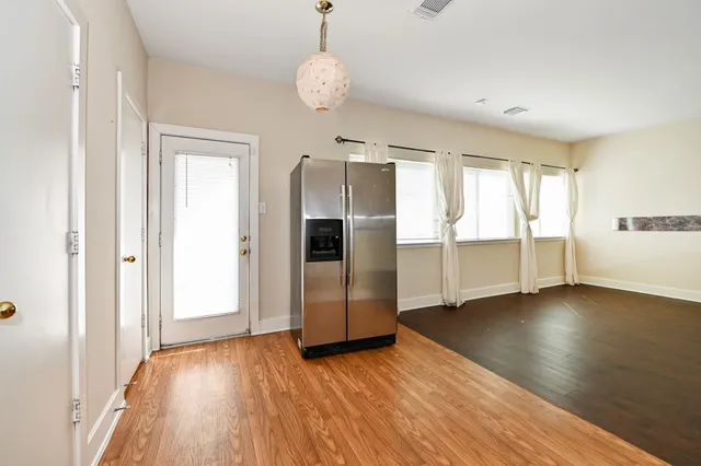an empty room with wooden floor staircase and windows