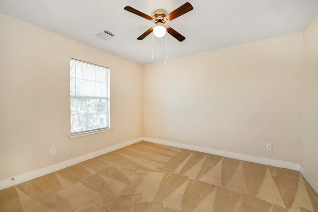 an empty room with a window and a fan
