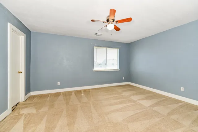 a view of an empty room with chandelier fan