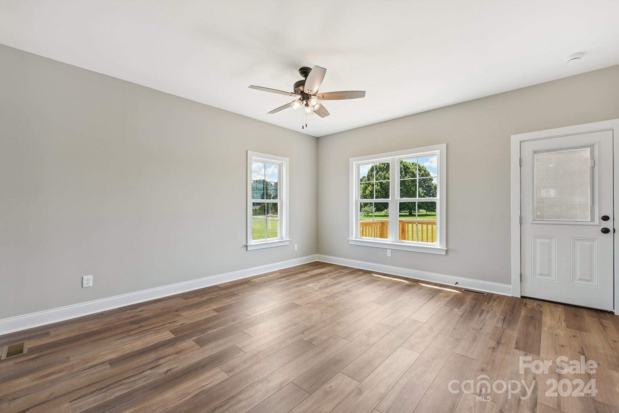 158 Wetmore Road Woodleaf, NC 27054 - Photo 5 of 33 an empty room with wooden floor ceiling fan and windows