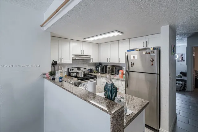 a kitchen with a refrigerator a stove a sink and a center island with wooden floor