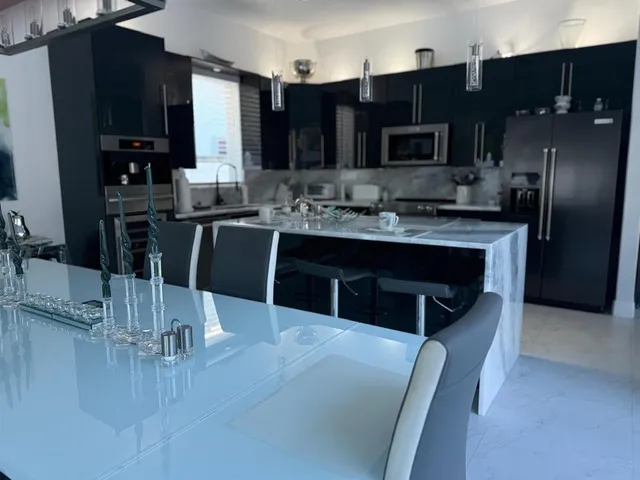 a kitchen with stainless steel appliances kitchen island granite countertop a sink refrigerator and cabinets