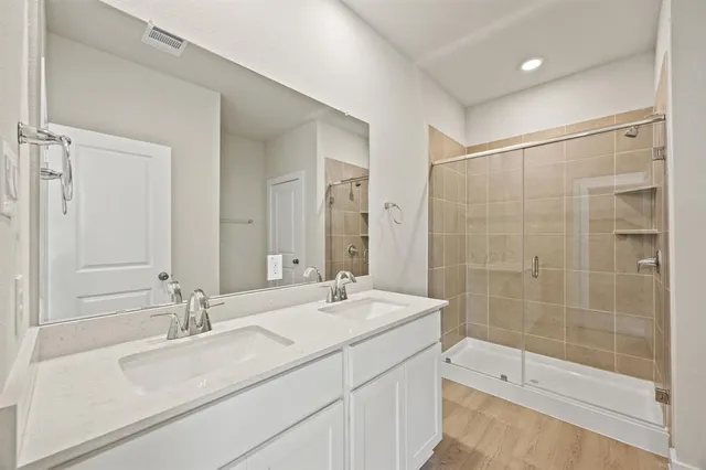 a bathroom with a sink double vanity and a glass door shower