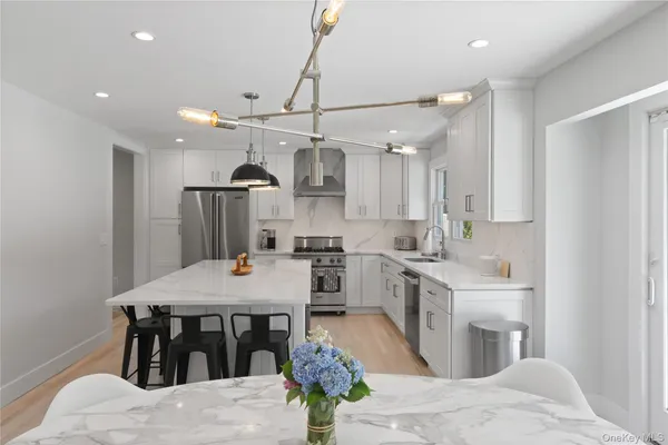 a kitchen with stainless steel appliances kitchen island granite countertop a sink a refrigerator and a stove