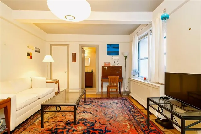 a living room with furniture a flat screen tv and a window