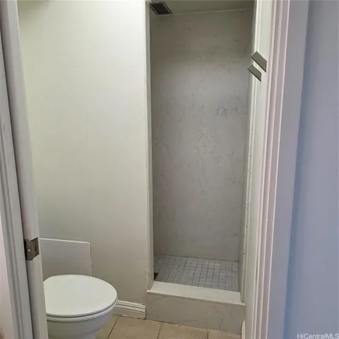 a white toilet next to a shower