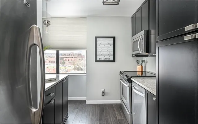 a kitchen with granite countertop a refrigerator a sink and wooden floors