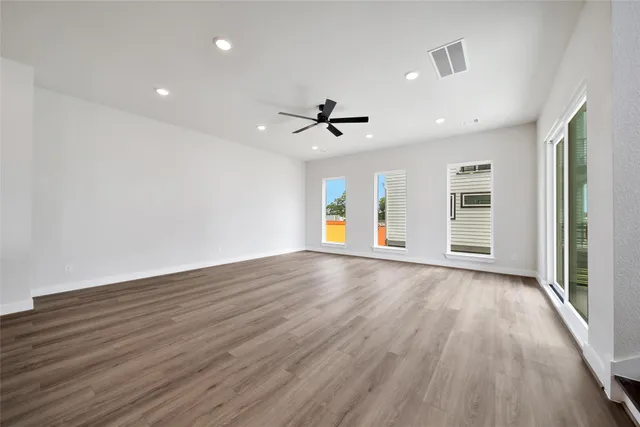 an empty room with wooden floor and windows