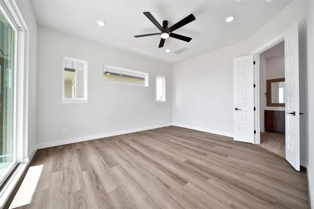 an empty room with wooden floor and a ceiling fan